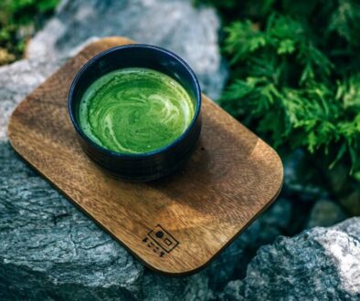 Green Tea in a black cup on arock in a forest